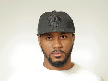 Black on black cap with tonal front embroidery, curved brim, and adjustable strap for minimalist unisex streetwear